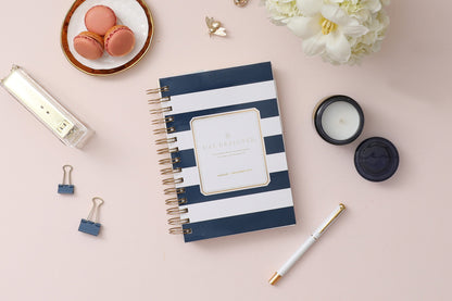 2025 daily monthly from day designer for blue sky featuring a hardcover, navy blue and white stripe design, gold twin wire-o binding in a compact 5x8 planner size.