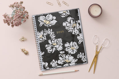 8.5x11 weekly monthly planner for January 2025 - December 2025 new year featuring silver twin wire-o binding, black/gray background, white florals and gold accents