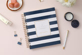2025 daily monthly from day designer for blue sky featuring a hardcover, navy blue and white stripe design, gold twin wire-o binding in a compact 8x10 planner size.
