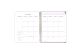 2025 planner featuring a monthly spread with lined and blank writing space, bullet points, and monthly white tabs with purple text.
