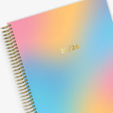 ombre rainbow 7x9 weekly monthly planner with gold wiire-binding on this July 2025-2026 academic planner